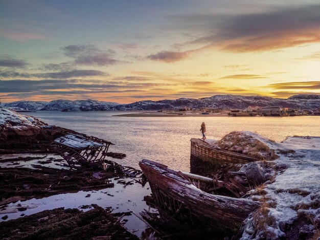 Kerkhof van schepen, zonsondergang in de winter in een oud vissersdorp aan de oever van de Barentsz-zee, het schiereiland Kola, Teriberka, Rusland.