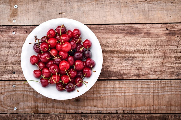 Kers met waterdruppels op witte kom op donkerbruine stenen tafel. Verse rijpe kersen. Zoete rode kersen. Bovenaanzicht. Rustieke stijl. Fruit Achtergrond