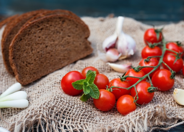 Kersen, grijs brood, lente-uitjes, knoflook op donkere rustieke achtergrond