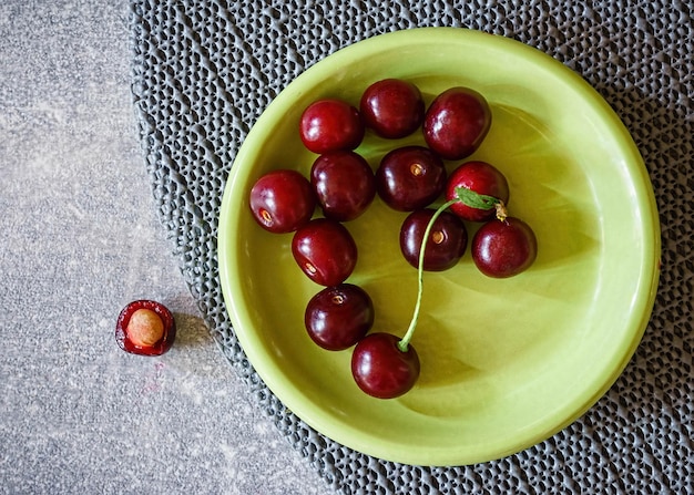 Kersen in een groen bord op een grijsmarmeren tafel