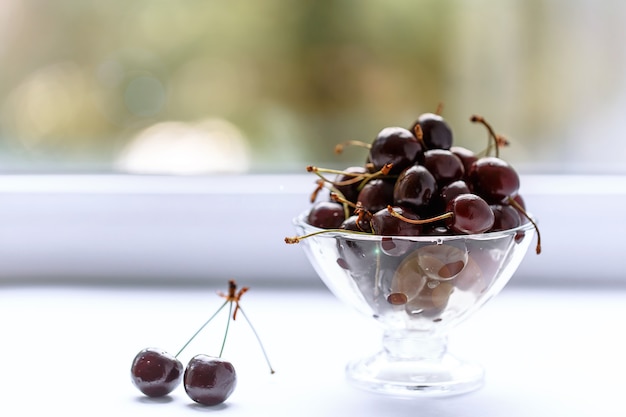 Kersen in een vaas met waterdruppels op tafel