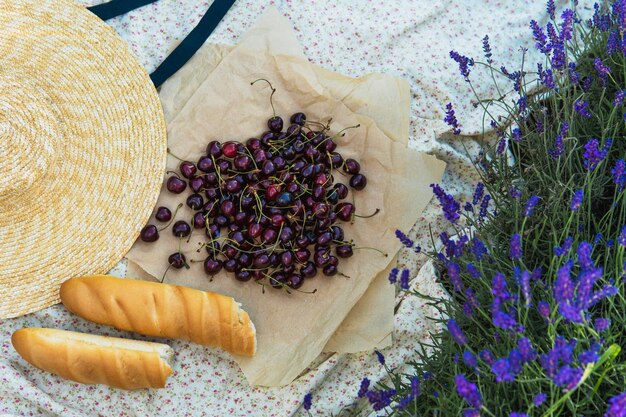 Kersenbessen en stokbrood op de deken tijdens picknick in het lavendelveld