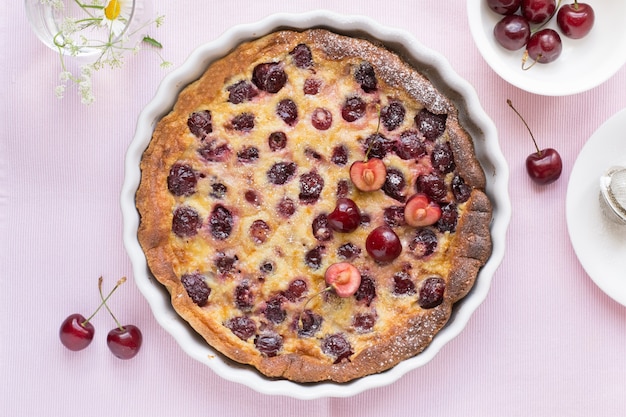 Kersenclafoutis in ovenschaal op roze tafel