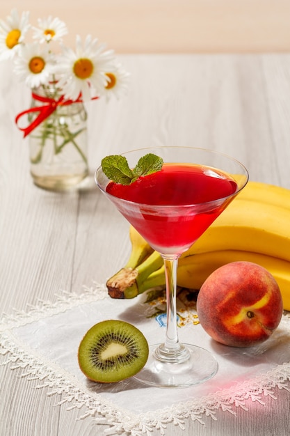 Kersengelei in de met glas bedekte muntblaadjes, nectarine, kiwi, banaan en boeket kamilles op de houten achtergrond