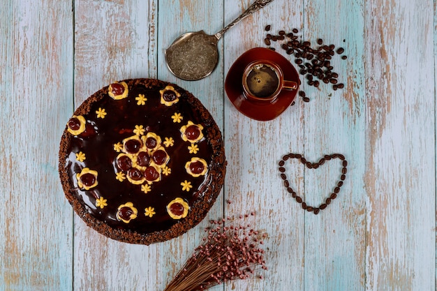 Kersentaart met chocolade glazuur, kopje koffie en bloemen