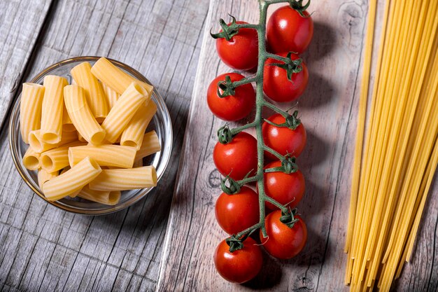 Kersentomaten en verse pasta op een houten voet.