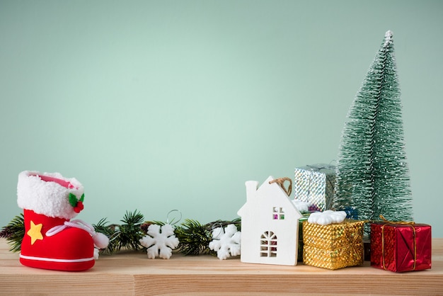 Kerst achtergrond. Een kleine kerstboom en dozen met geschenken op een houten tafel. Groene achtergrond. Ruimte voor tekst.