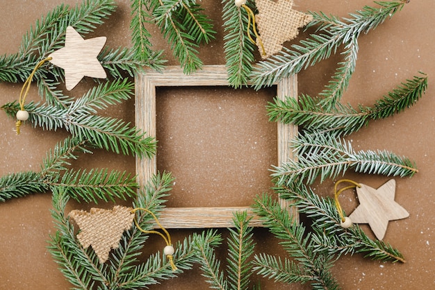 Kerst achtergrond met fir takken en houten ornamenten op een bruine tafel.