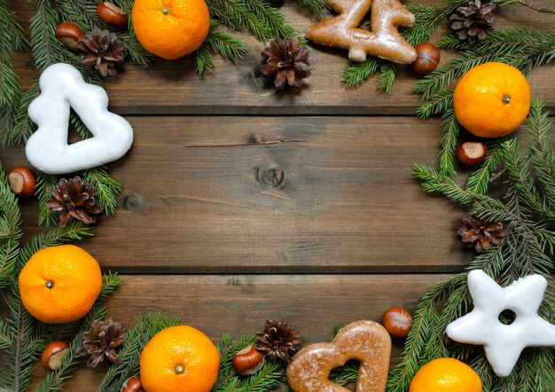 Foto kerst achtergrond met fir takken, kegels, mandarijnen, noten en peperkoek