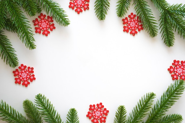 Kerst achtergrond met groene fir takken en rode sneeuwvlokken