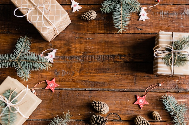 Kerst achtergrond samengesteld uit verpakte geschenkdozen, dennenappels, naaldbomen, decoratieve rode sterren en witte sparren