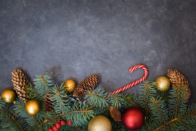 Kerst achtergrond van dennentakken, kerstballen en snoepjes, dennenappels.