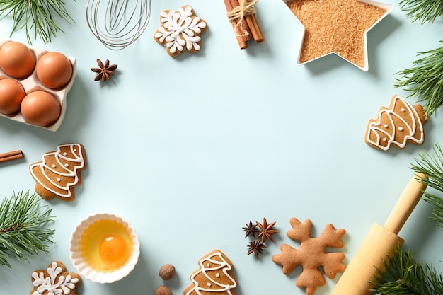 Kerst bakken achtergrond met koekjes en ingrediënten op blauwe achtergrond. Kopieer ruimte. Uitzicht van boven.