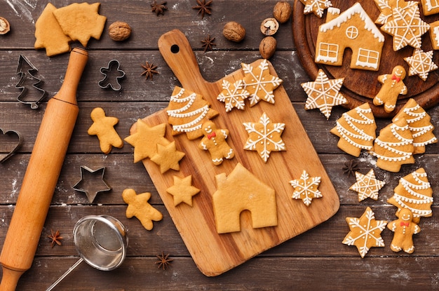 Kerst bakken. Koekjes van verschillende vormen met suikerglazuur op snijplank over houten ondergrond, bovenaanzicht