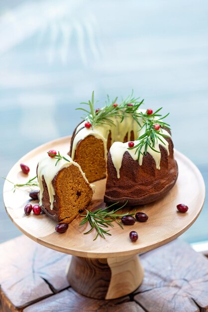 Kerst caramel cake, cutaway, versierd met witte chocolade, veenbessen en rozemarijn op een houten standaard. Feestelijke gebakken goederen. Zachte selectieve focus. Verticaal