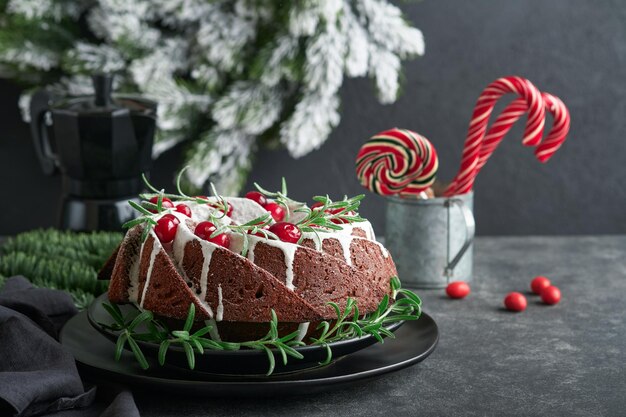 Kerst chocolade bundt cake Traditionele kerstfruitcake met witte glazuur veenbessen en rozemarijn op donkere achtergrond Kerstdecoratie Winter bakken met Kerstmis of Nieuwjaar Kopieer ruimte