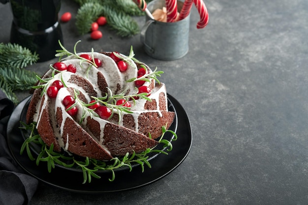 Kerst chocolade bundt cake Traditionele kerstfruitcake met witte glazuur veenbessen en rozemarijn op donkere achtergrond Kerstdecoratie Winter bakken met Kerstmis of Nieuwjaar Kopieer ruimte