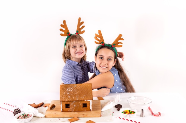 Foto kerst concept twee kinderen maken peperkoek huis geïsoleerd op een witte achtergrond
