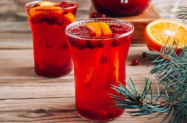 Kerst cranberry punch met sinaasappelen in een kruik en glazen op rustieke houten tafel