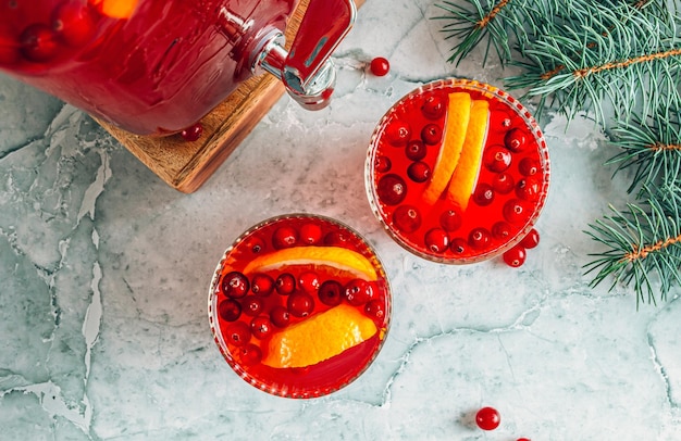 Kerst cranberry punch met sinaasappels in een kruik en glazen op grijze marmeren tafel