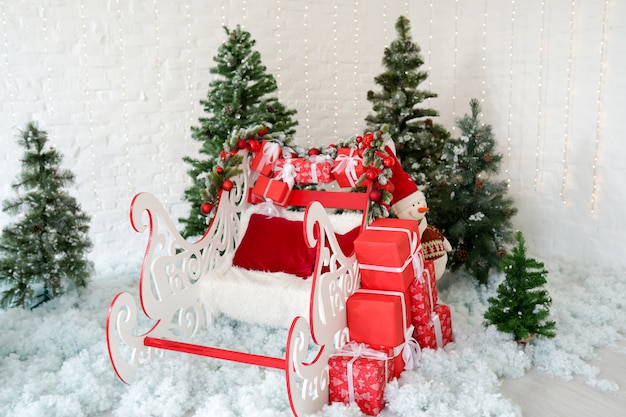 Kerst decor slee en rode geschenkdozen met groene kerstbomen op sneeuw