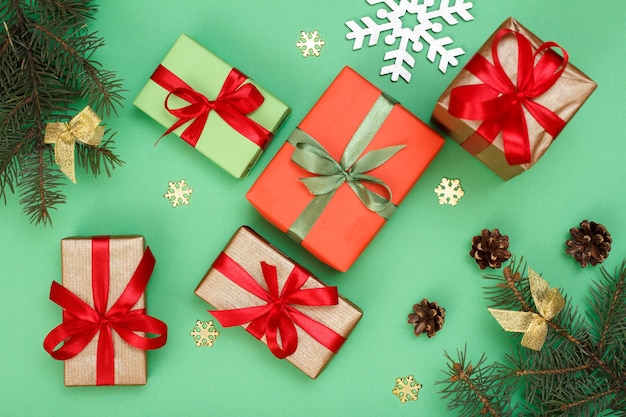 Kerst decoratie. Geschenkdozen, sparren takken met kegels en decoratieve sneeuwvlokken op groene achtergrond. Bovenaanzicht. Kerst wenskaart concept.