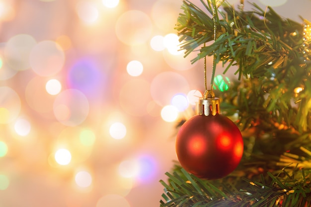 Kerst decoratie. Het hangen van rode ballen op de Kerstboomslinger en ornamenten van pijnboomtakken over samenvatting bokeh met exemplaarruimte