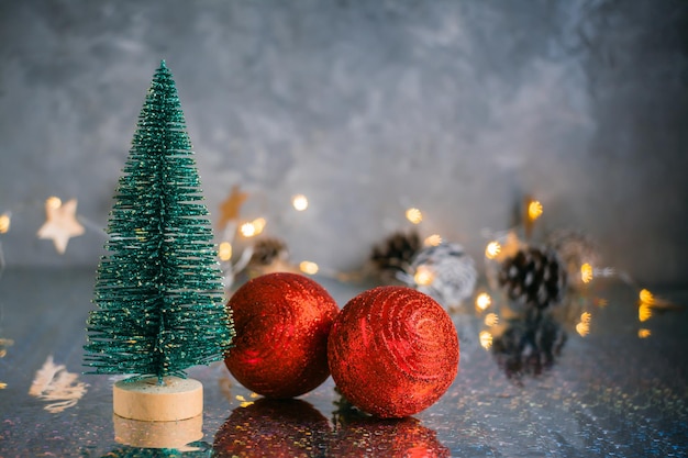 Kerst decoratieve pluizige spar en twee rode glanzende ballen op een grijze achtergrond met wazige lichten. Kerstmis achtergrond. Ruimte kopiëren