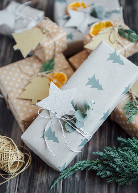 Foto kerst decoratieve zelfgemaakte geschenkdozen verpakt in bruin kraftpapier op een donkergrijze houten ondergrond