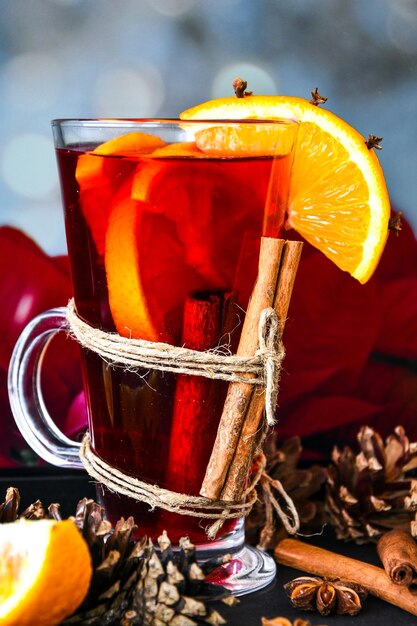 Kerst drankje. Glazen warme glühwein met sinaasappels, anijs en kaneel naast de rode kerststerbloem. Vakantiesfeer, rustieke stijl. Het idee om wenskaarten te maken