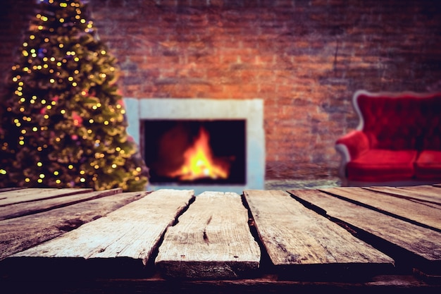 Kerst en Nieuwjaar achtergrond met lege donkere houten dek tafel over kerstboom en wazig licht bokeh. Leeg scherm voor product montage. Rustieke vintage Kerstmis achtergrond.