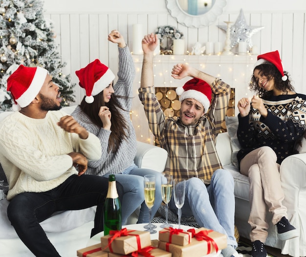 Kerst- en nieuwjaarsfeest. jonge gelukkige vrienden in kerstmutsen die thuis dansen, kopieer ruimte