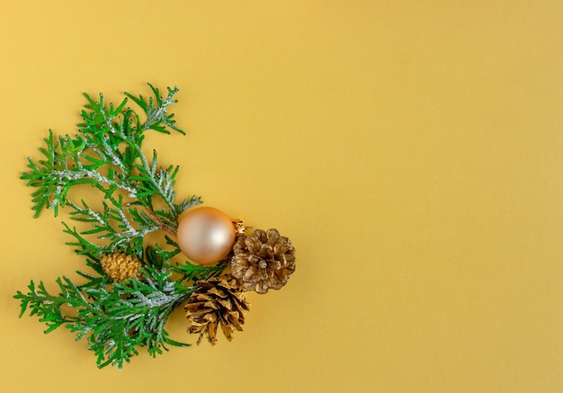 Kerst- en nieuwjaarskaart achtergrond dennenboom en kegels op geelgouden achtergrond plat lag kopie sp...