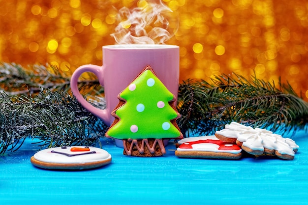 Kerst- en nieuwjaarskoekjes in de buurt van een mok met hete thee of koffie en dennentakken feestelijke kerstsfeer