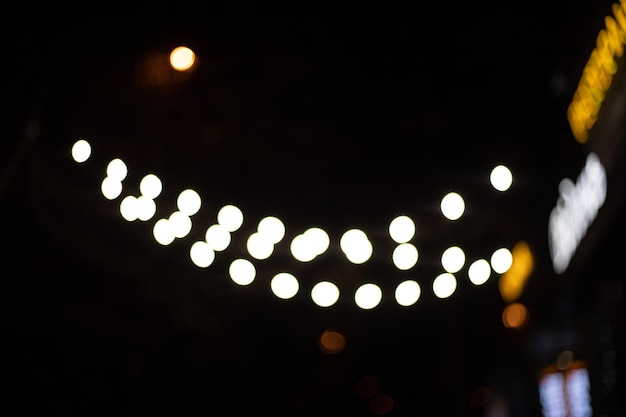 Kerst- en nieuwjaarsslinger op straat bij het uithangbord van het café tegen de achtergrond van de donkere lucht. Zachte focus. Onscherpe achtergrond.