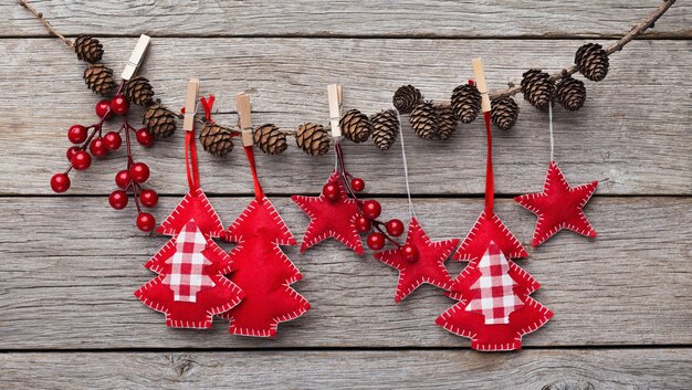 Kerst- en nieuwjaarsversieringen gemaakt van vilt hangen aan een stok met dennenappels, rustieke houten achtergrond, kopieerruimte