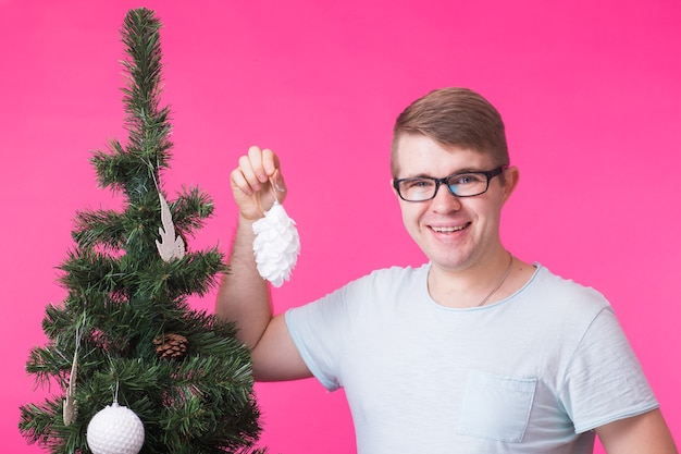 Kerst- en vakantieconcept - Portret van lachende man met kerstboom op roze muur.