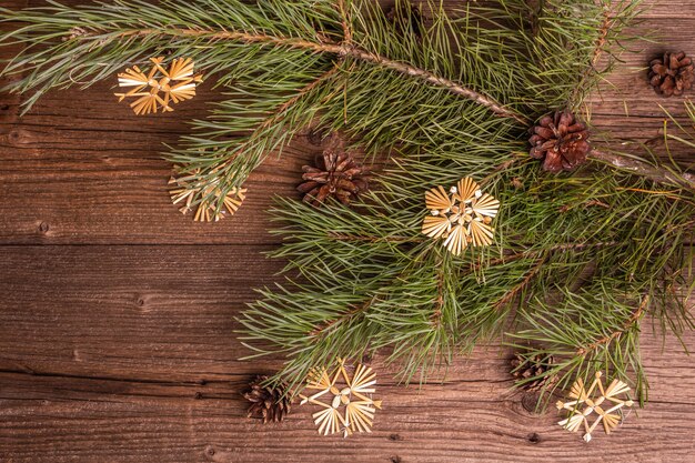 Foto kerst feestelijke oude houten achtergrond. geen afval kerst decor concept. verse groenblijvende pijnboomtakken en strosneeuwvlokken, plat gelegd