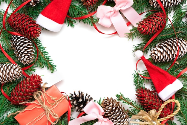 Kerst frame gemaakt van fir takken en kegels op een witte achtergrond met linten.