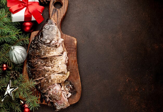 Kerst gebakken karper op een stenen tafel met bomen en speelgoed met kopie ruimte