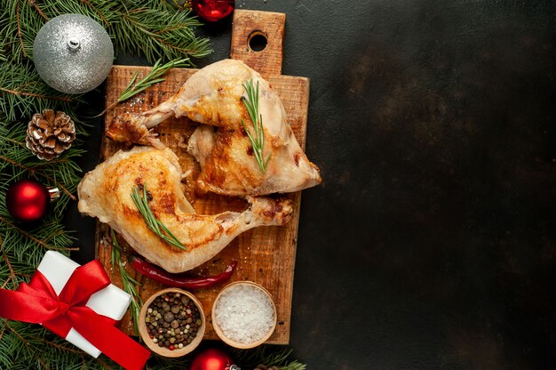 kerst gegrilde kippenpoten met specerijen en kruiden, met kerstbomen en speelgoed, dragers op een stenen achtergrond.