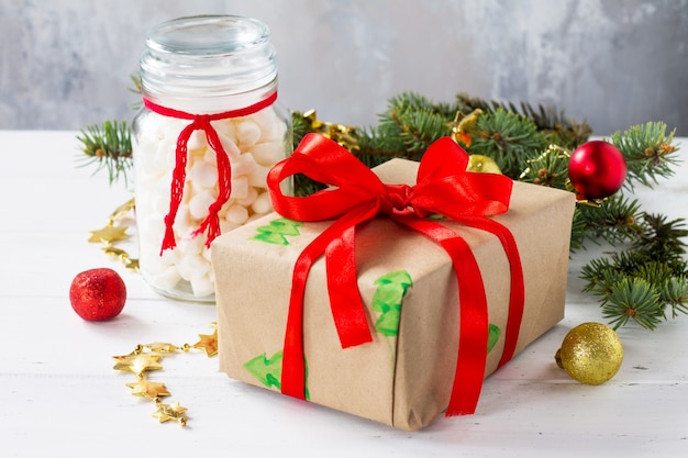 Kerst geschenkdozen en een potje marshmallows met een kerstboom op een witte houten tafel