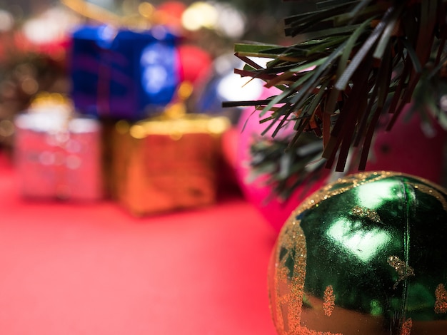 Kerst geschenkdozen verpakt in verschillende kleuren onder kerstboom op rode achtergrond. . Feestelijk interieur.