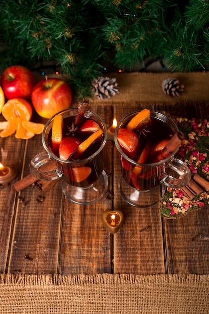 Kerst glühwein met fruit, kaarsen en kruiden op houten tafel.