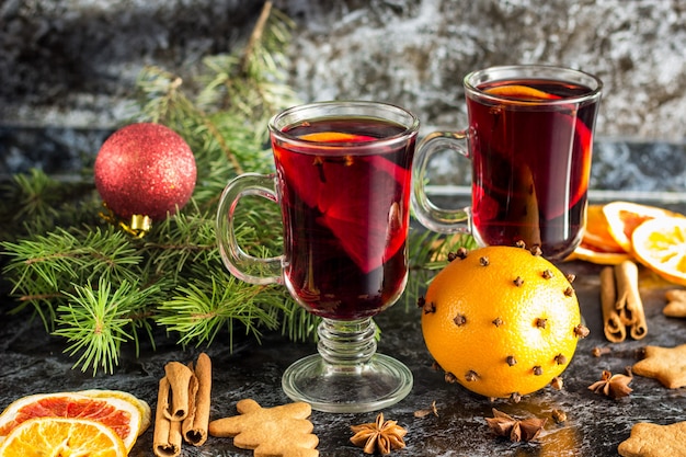 Kerst glühwein met gemberkoekjes oranje kaneel kruidnagel anijs en fir tree op de donkere tafel