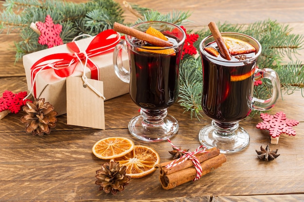 Kerst glühwein met kruiden en sinaasappelen op een rustieke houten tafel. Traditionele warme drank met Kerstmis met cadeaus