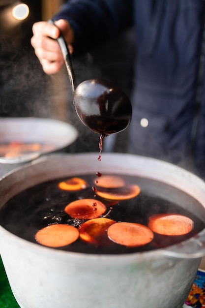 Kerst glühwein op de kermis gebrouwen in een ketel met kaneel en citrus Koken van een traditioneel kerst- en nieuwjaarsdrankje