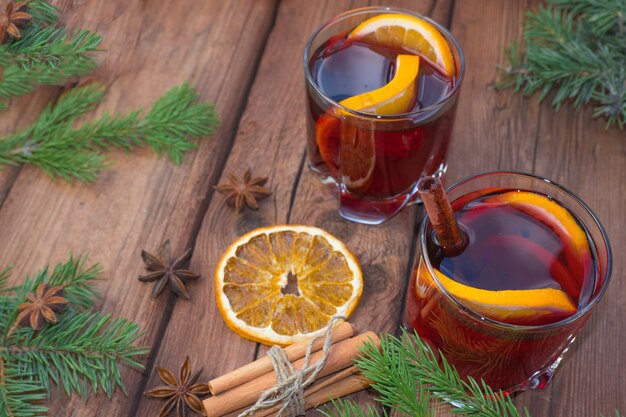 Kerst glühwein op een houten ondergrond met kruiden en vuren takken en gedroogde sinaasappel