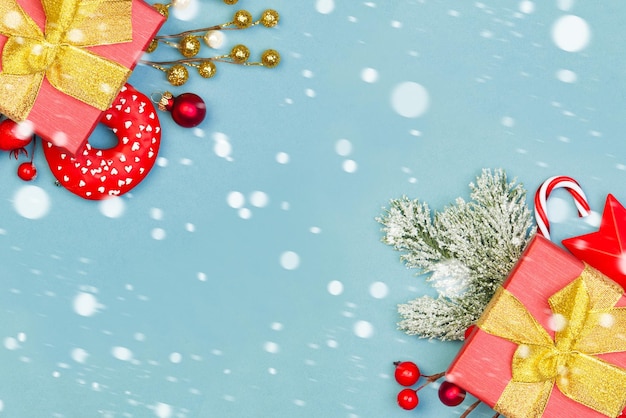 Kerst grens achtergrond. Rode geschenken, hulstbessen en groene spartak op blauwe achtergrond met kopieerruimte met sneeuw