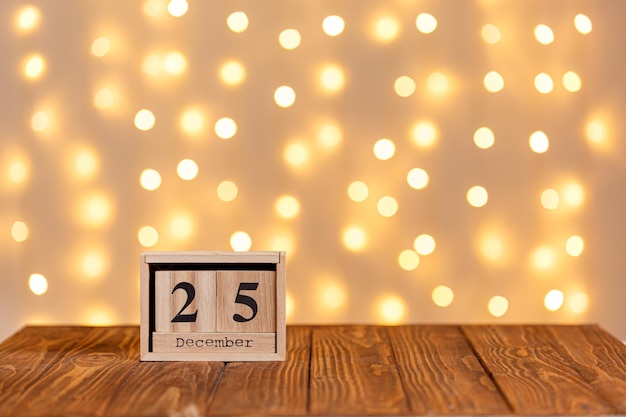 Kerst houten kalender 25 december op houten achtergrond en verlichting achtergrond